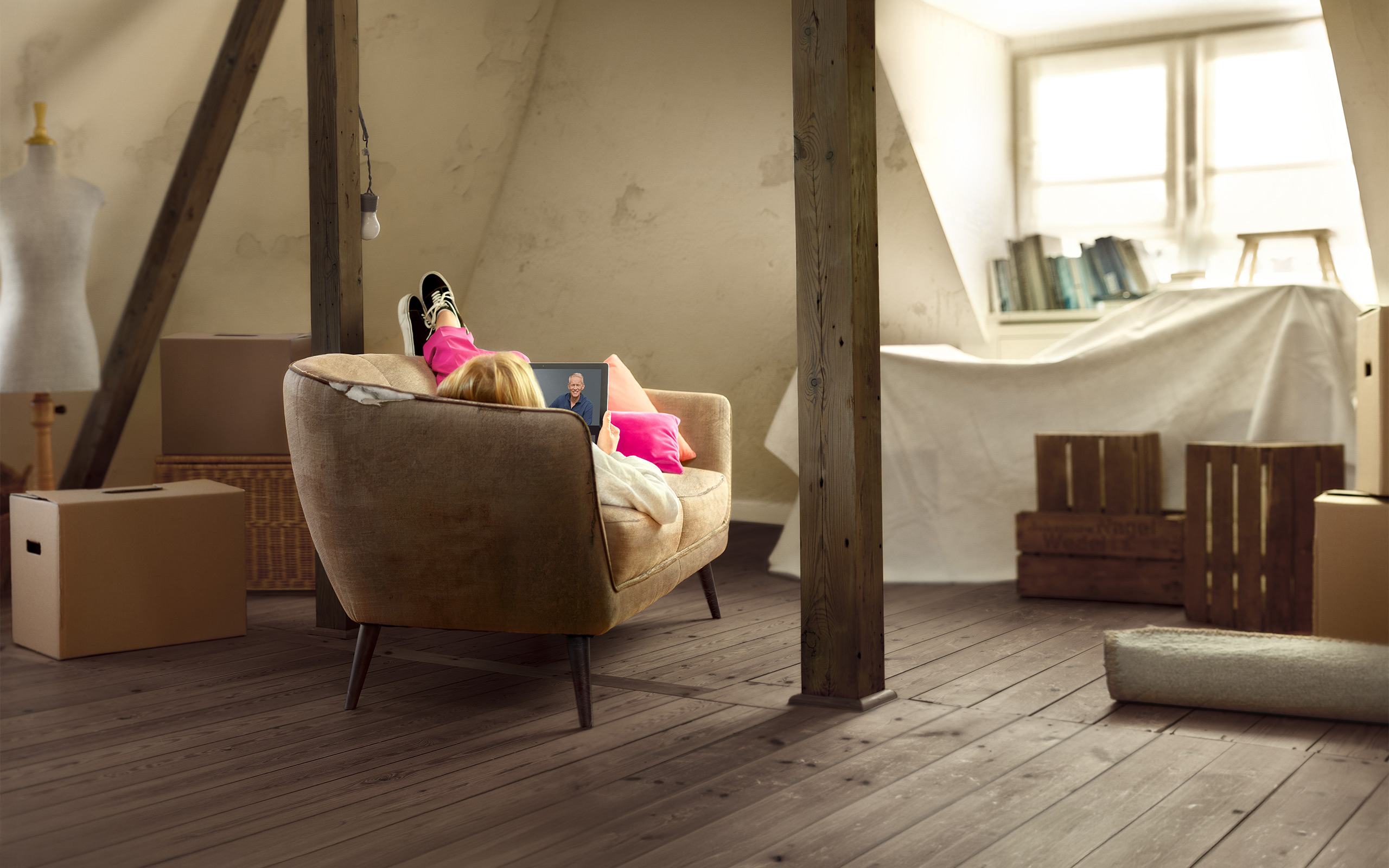 Eine Person liegt entspannt auf einem Sofa in einem hellen, renovierten Dachbodenraum.