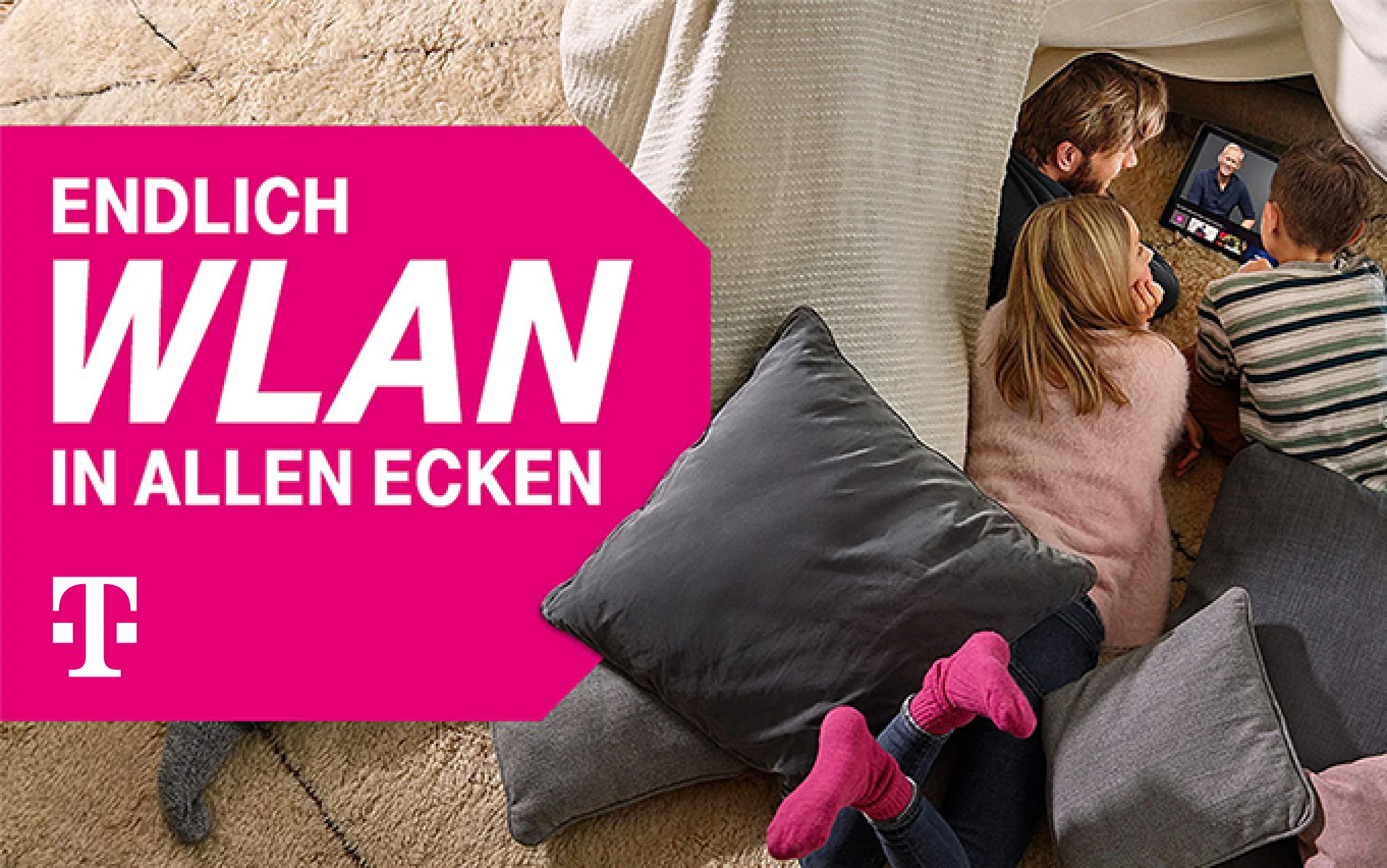 Familie sitzt entspannt auf Kissen und schaut gemeinsam ein Video auf einem Tablet.