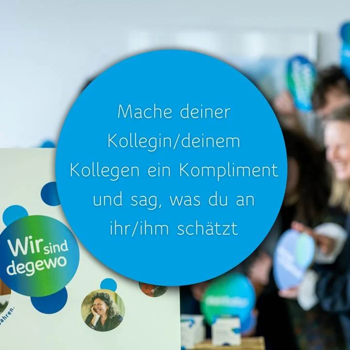 Ein blauer Kreis mit weißem Text fordert auf, Kolleginnen und Kollegen ein Kompliment zu machen.